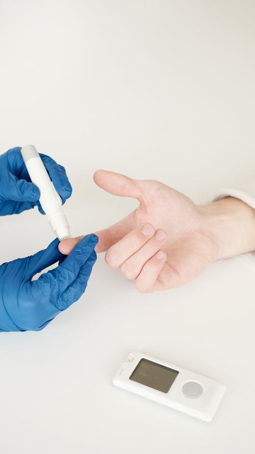 Free A healthcare professional tests blood sugar with a glucometer and lancet pen in a medical setting. Stock Photo